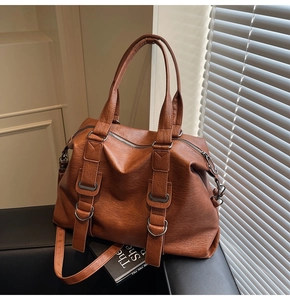 Detail view of brown vintage PU leather tote bag with metallic buckle and shoulder strap