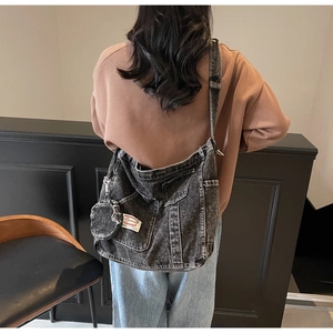 Detail view of large charcoal gray washed denim crossbody bag with multiple pockets