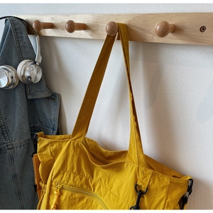 Detail of a large yellow nylon tote bag featuring wrinkled texture and black metal buckle