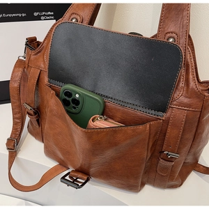 Detailed view of brown lychee leather handbag with spacious front pocket and metal buckles