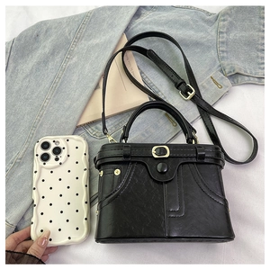 Detail of black leather box bag with creative jacket pocket design and gold hardware