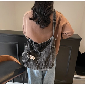 Detail of grey washed denim crossbody bag featuring a round coin purse and cargo style pockets