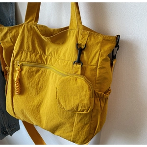 Detailed view of yellow nylon tote bag with side pocket and matching round mini pouch