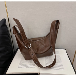 Close-up of brown matte leather dumpling bag featuring wide strap and silver ring buckle