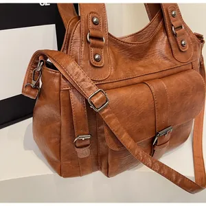 Detailed side view of brown vintage PU leather handbag with large buckle pocket and strap