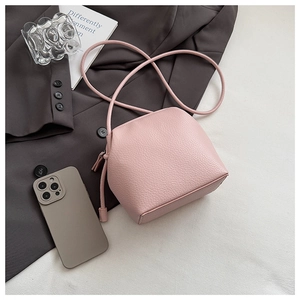 Detail of pink lychee grain leather crossbody bag with drawstring design and long strap