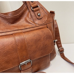 Detail of brown faux leather handbag with vintage texture and silver buckle hardware