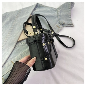 Detail of black oil-wax leather bucket bag with gold rivets on denim background