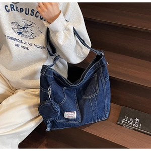 Detail of vintage blue denim crossbody bag with multiple pockets and adjustable strap