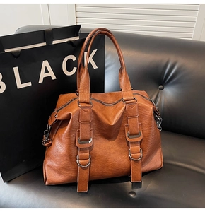 Close-up of caramel brown tote bag featuring pebbled leather texture and metal D-ring detail