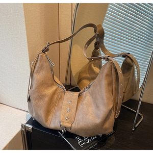 Detail of a brown leather crescent tote bag featuring silver star rivets and soft texture