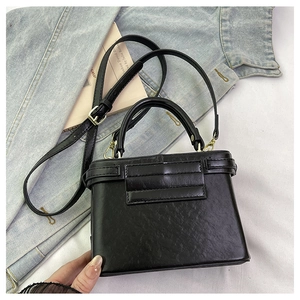 Detail of black pebbled leather handbag with gold hardware and removable shoulder strap
