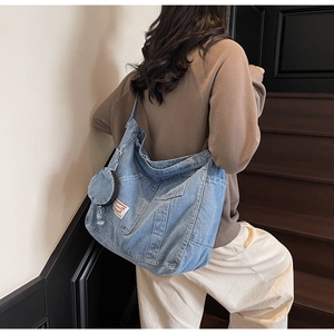 Detail of vintage denim crossbody bag featuring utility pockets and a small coin pouch