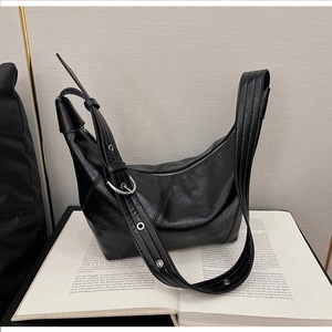 Detail of black crescent shoulder bag with V-shaped stitching on an open book