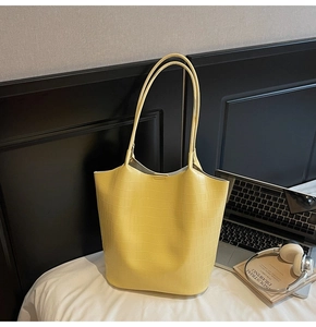 Κίτρινη τσάντα tote με κροκό σχέδιο δίπλα σε laptop και ακουστικά σε σκηνή σπιτιού
