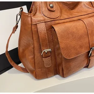 Detailed close-up of caramel brown tote bag showing pebbled leather and silver buckle