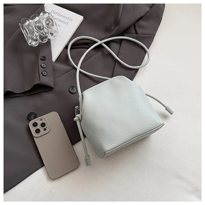 Detailed close-up of mint green litchi grain leather bag with knotted shoulder strap