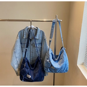 Detail of vintage washed denim crossbody bag featuring utility pockets and small round pouch