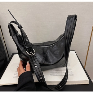Detail of black dumpling shoulder bag with wide grommet strap and silver buckle