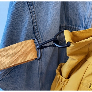 Macro detail of black metal D-ring buckle on yellow nylon tote bag with fabric texture