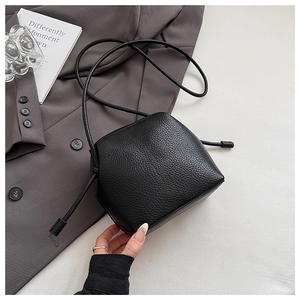 Detail showing the black litchi grain leather texture and drawstring closure of the crossbody bag