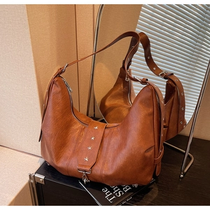 Detail of vintage brown crescent tote with silver star rivets and adjustable strap