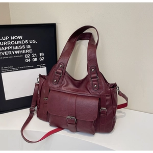 Detail of burgundy faux leather tote bag featuring a front flap pocket and woven strap