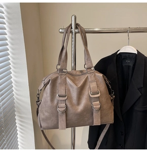 Detail of taupe tote bag showing pebbled leather texture and silver buckle hardware