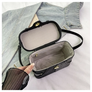 Top view of black embossed box bag open with gray herringbone lining and inner zipper pocket