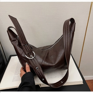 Close-up of dark brown crescent bag with polished silver eyelet strap and smooth metal zipper