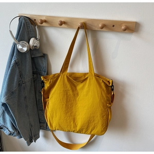 Close-up of vibrant yellow nylon tote bag hanging with headphones in home setting