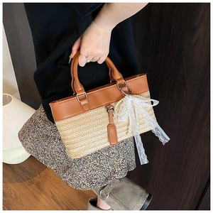 Detail of the straw weave texture and brown leather trim with a pearl bow charm