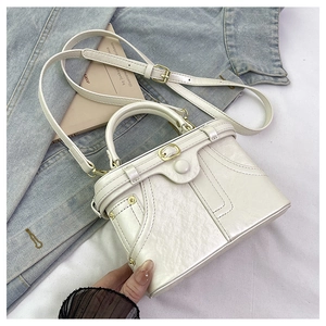 Close-up of cream-white purse with denim jacket design elements and golden metal studs