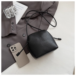 Detail shot of black pebbled leather shell bag with drawstrings on a professional setup