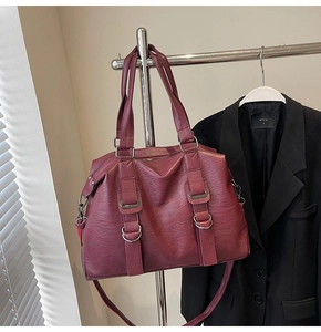 Detailed close-up of dark red tote bag featuring grainy faux leather texture and metal buckle
