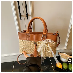 Detailed view of straw-leather patchwork tote bag with pearl lace bow charm