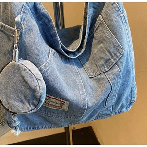 Detail view of large denim tote bag with visible stitching and attached round coin pouch