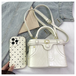 Detail of a white faux leather box bag with litchi texture and gold metal buckle