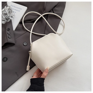 Detail of creamy white lychee textured leather crossbody bag with smooth zipper closure