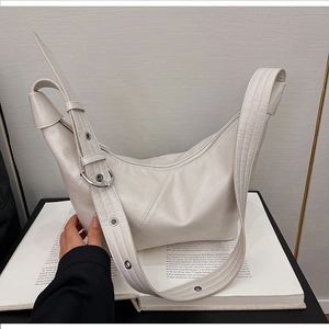 Detailed shot of white crescent shoulder bag featuring wide strap and silver metal hardware