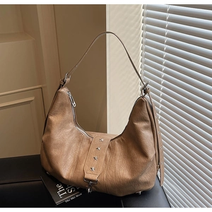 Detailed texture of tan hobo bag featuring silver star rivets and metal buckle closure