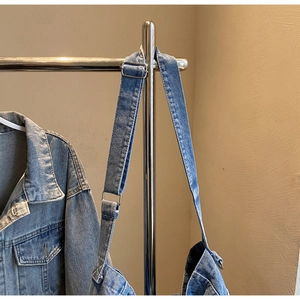 Close-up of blue washed denim crossbody bag featuring wide strap and silver metal buckle