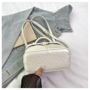 Detail view of cream white leather bag with litchi texture and gold metal buckle hardware