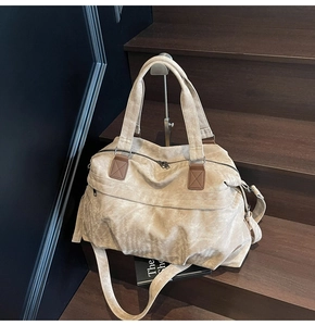 Dettaglio della borsa da viaggio in tela con toppe in pelle rinforzata e tracolla