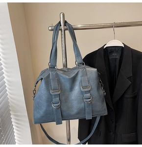 Detail of blue large tote bag with buckle and metal ring decor on silver rack