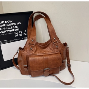Detail view of brown faux leather tote bag with vintage belt buckle and adjustable strap