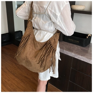Detail of brown suede tote bag with boho tassels and wide shoulder strap on model