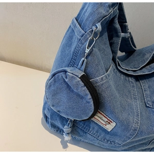 Detail of blue washed denim bag featuring a detachable round coin purse and metal hook