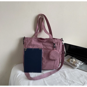 Close-up of mauve nylon tote bag featuring a matching small circular charm and tablet