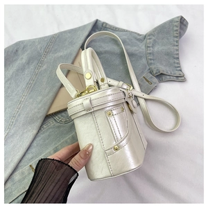 Macro view of pearlescent cylinder bucket bag with golden rivets and metallic hardware